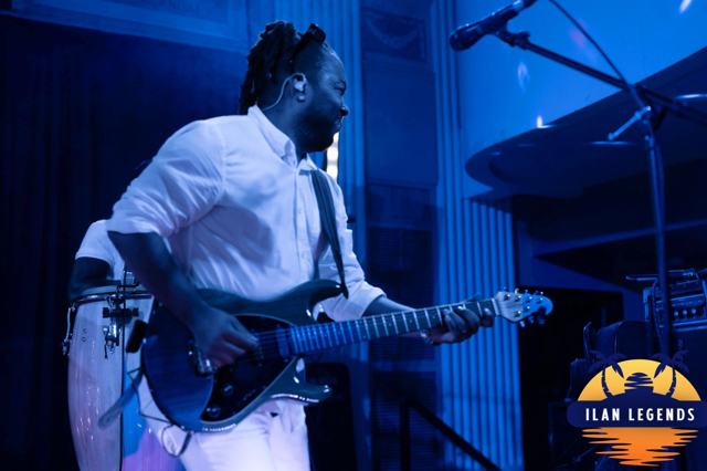 The guitarist playing under blue light