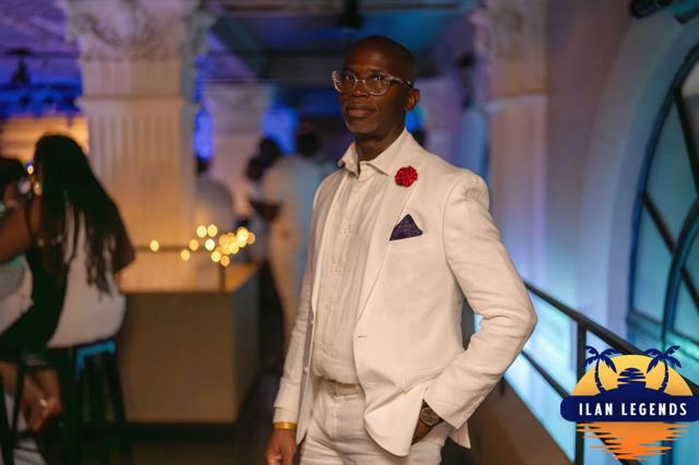 A guest in a white suit with a red rose